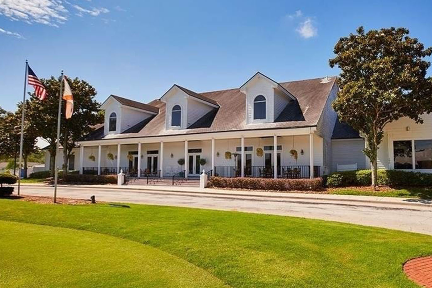 Deercreek Country Club wedding venue in Southside Jacksonville FL, white colonial-style clubhouse with covered front porch, manicured lawn, American flag
