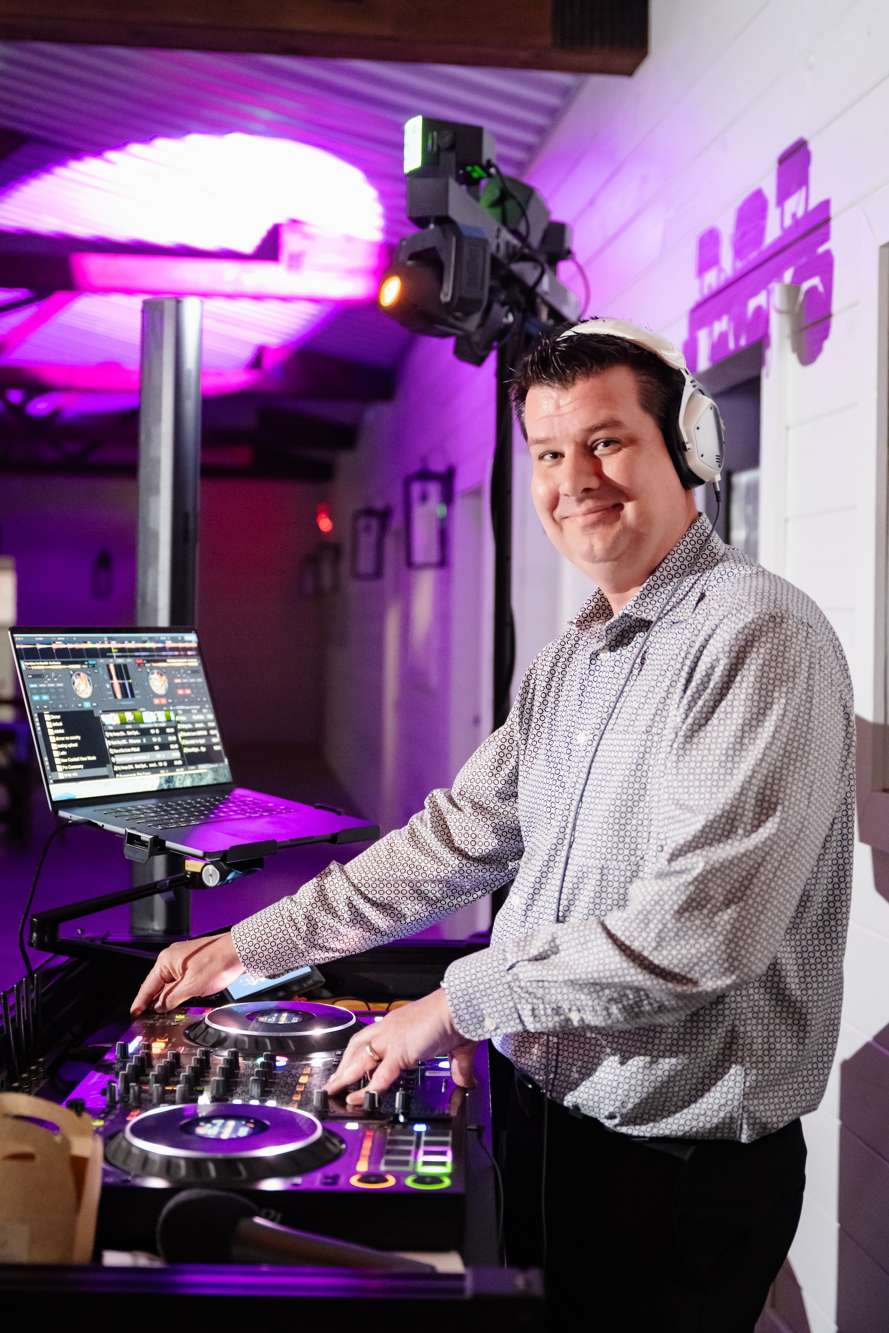 Footloose Entertainment DJ at the booth inside the Grand Cypress barn at Ancient City Farmstead near St. Augustine FL, Pioneer controller and laptop, purple uplighting and moving light behind