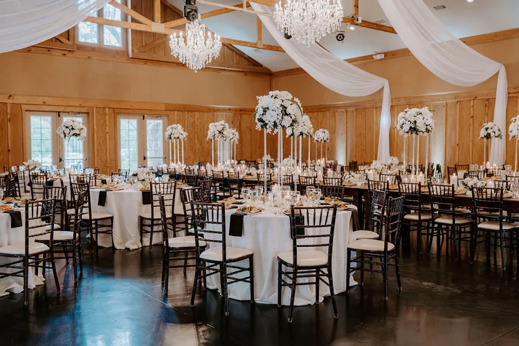 Bowing Oaks indoor reception hall with chandeliers and white floral centerpieces, Jacksonville FL