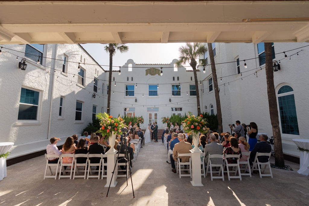 Outdoor courtyard wedding ceremony at Casa Marina Hotel with string lights and tropical florals, Jacksonville Beach FL