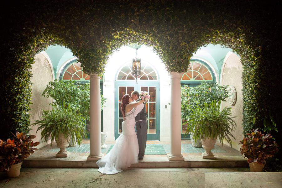 Bride and groom kissing under the ivy-covered arch at Club Continental Orange Park FL — Footloose Entertainment wedding DJ