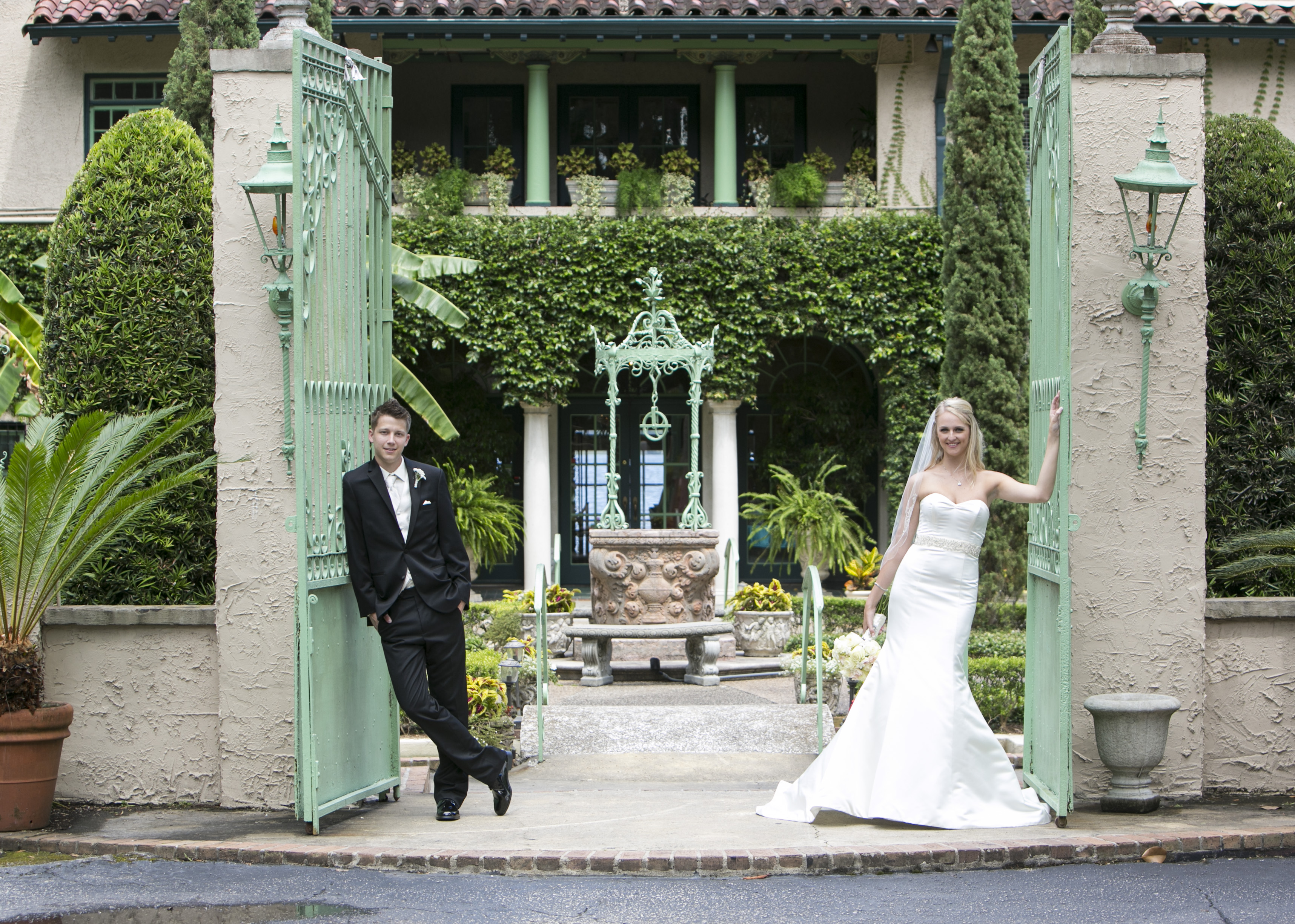 Bride and groom at the ornate green iron gates at Club Continental Orange Park FL with Mediterranean estate grounds behind them — Footloose Entertainment wedding DJ