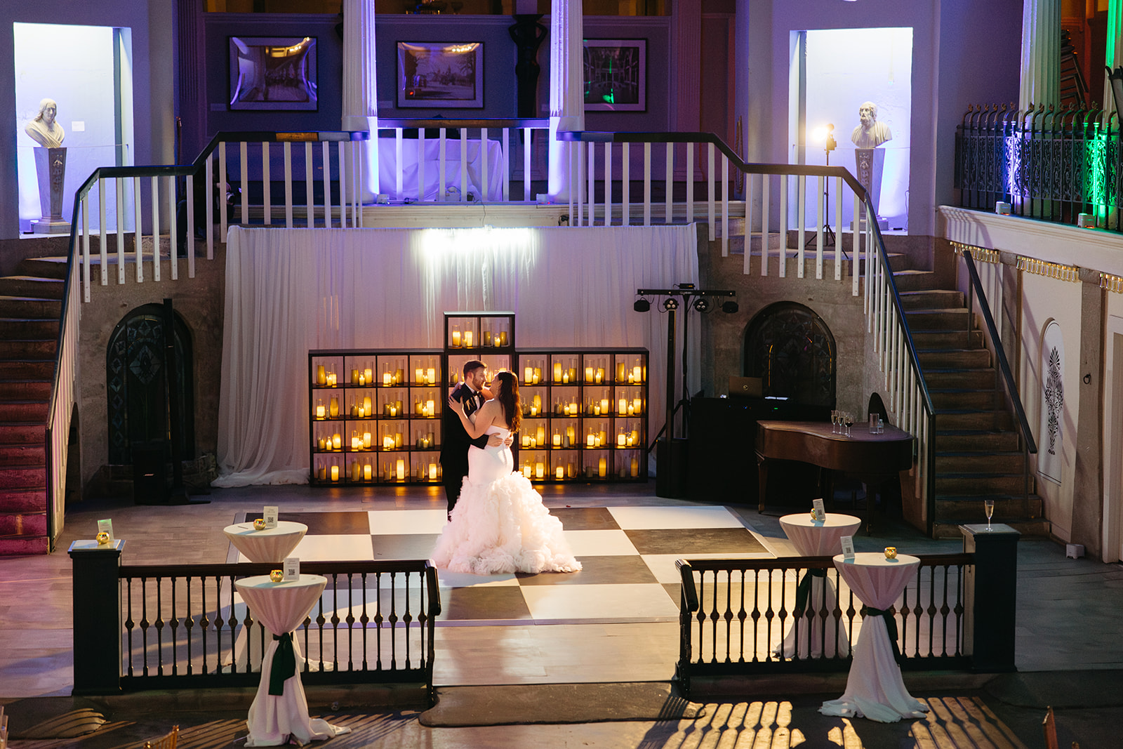 Bride and groom first dance on checkered dance floor at the Lightner Museum St. Augustine FL with candle wall backdrop and purple uplighting — Footloose Entertainment wedding DJ and lighting