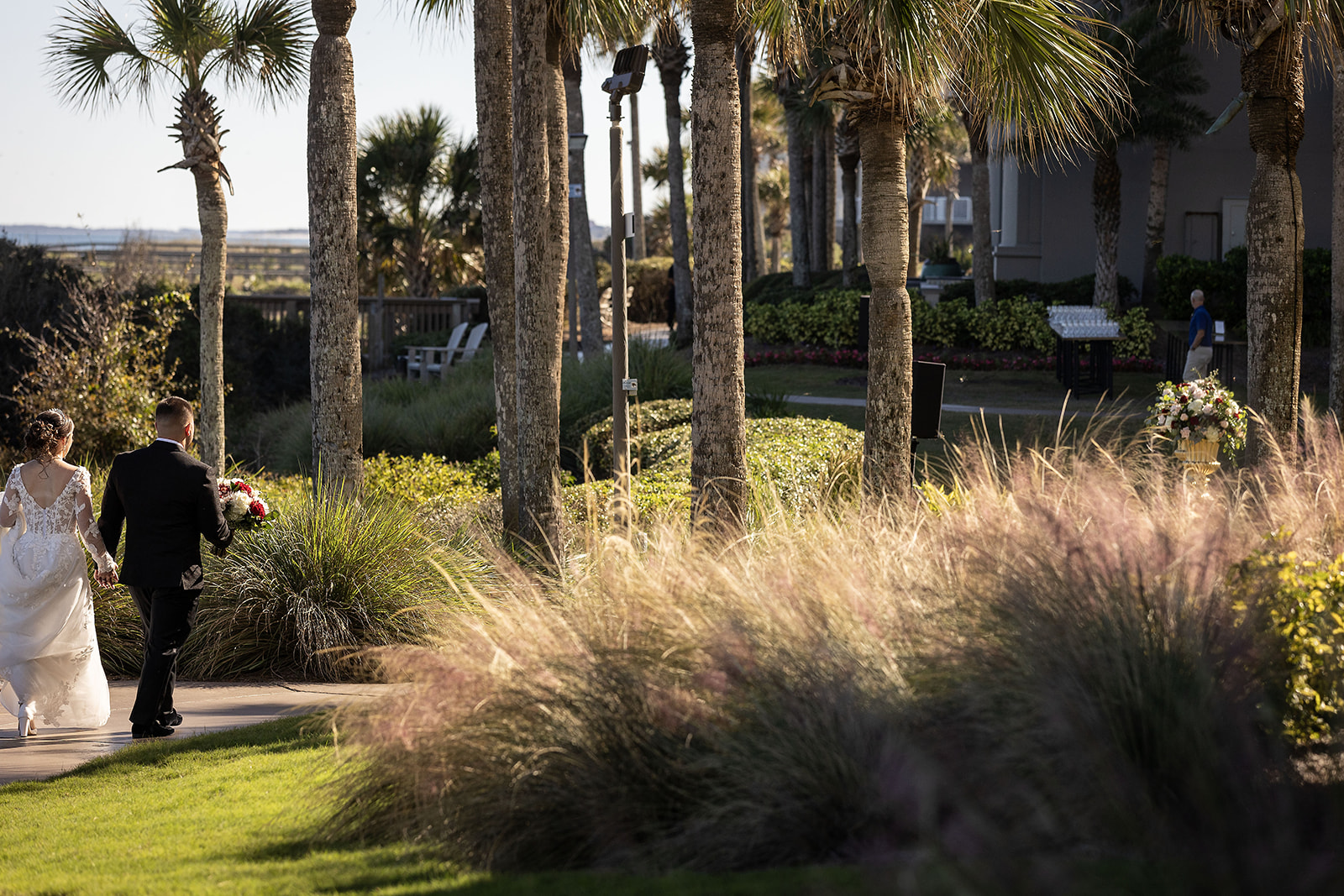 Bride and groom walking hand in hand through palm tree gardens at Ritz-Carlton Amelia Island FL — Footloose Entertainment wedding DJ