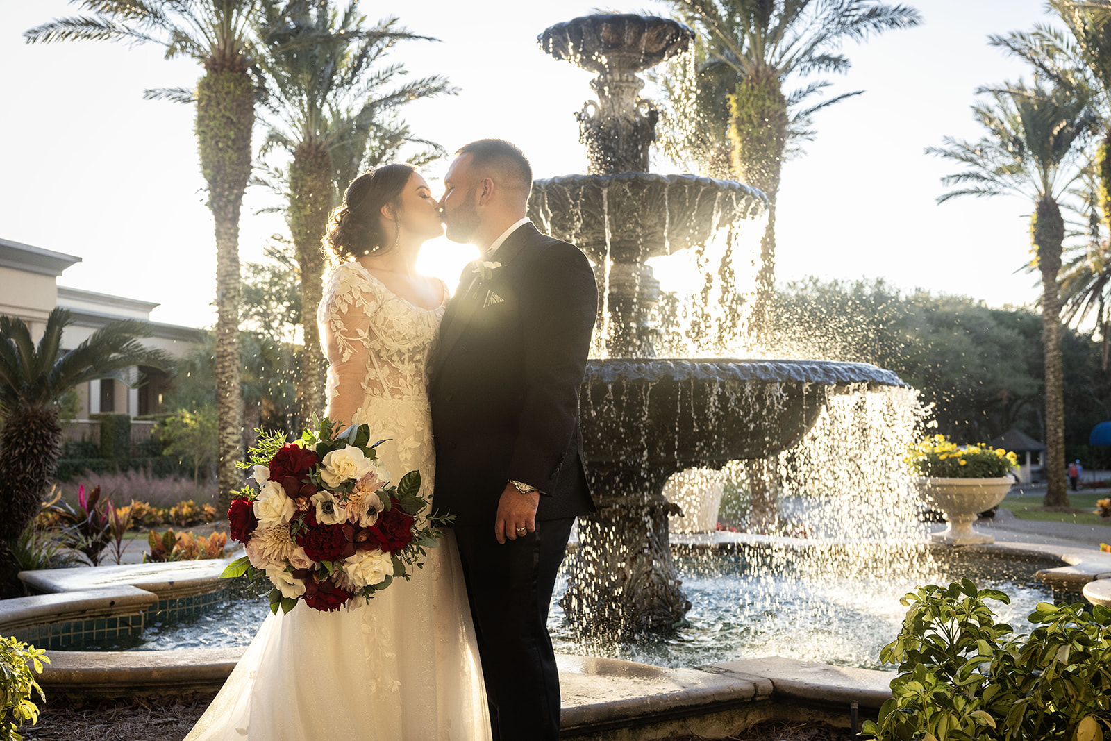 Bride and groom kissing at the fountain at golden hour at Ritz-Carlton Amelia Island FL with palm trees and tropical gardens — Footloose Entertainment wedding DJ