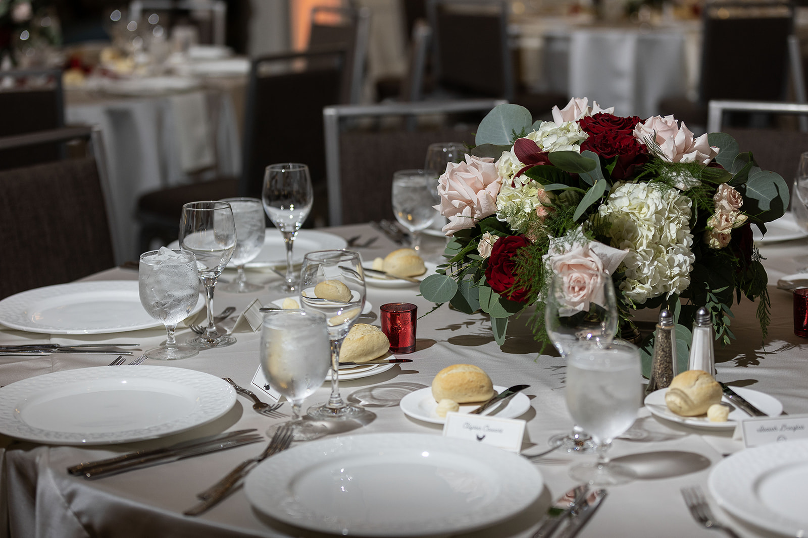 Ritz-Carlton Amelia Island FL wedding reception dinner table set with florals, glassware, and place settings in the ballroom — Footloose Entertainment wedding DJ
