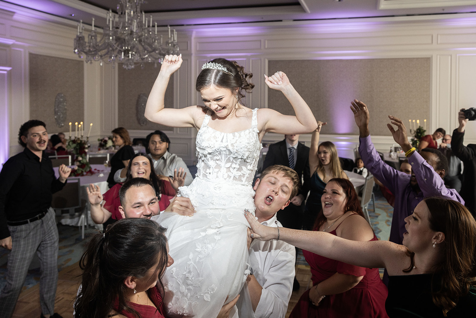 Bride lifted by guests on the dance floor at Ritz-Carlton Amelia Island FL with purple uplighting and crystal chandelier — Footloose Entertainment wedding DJ