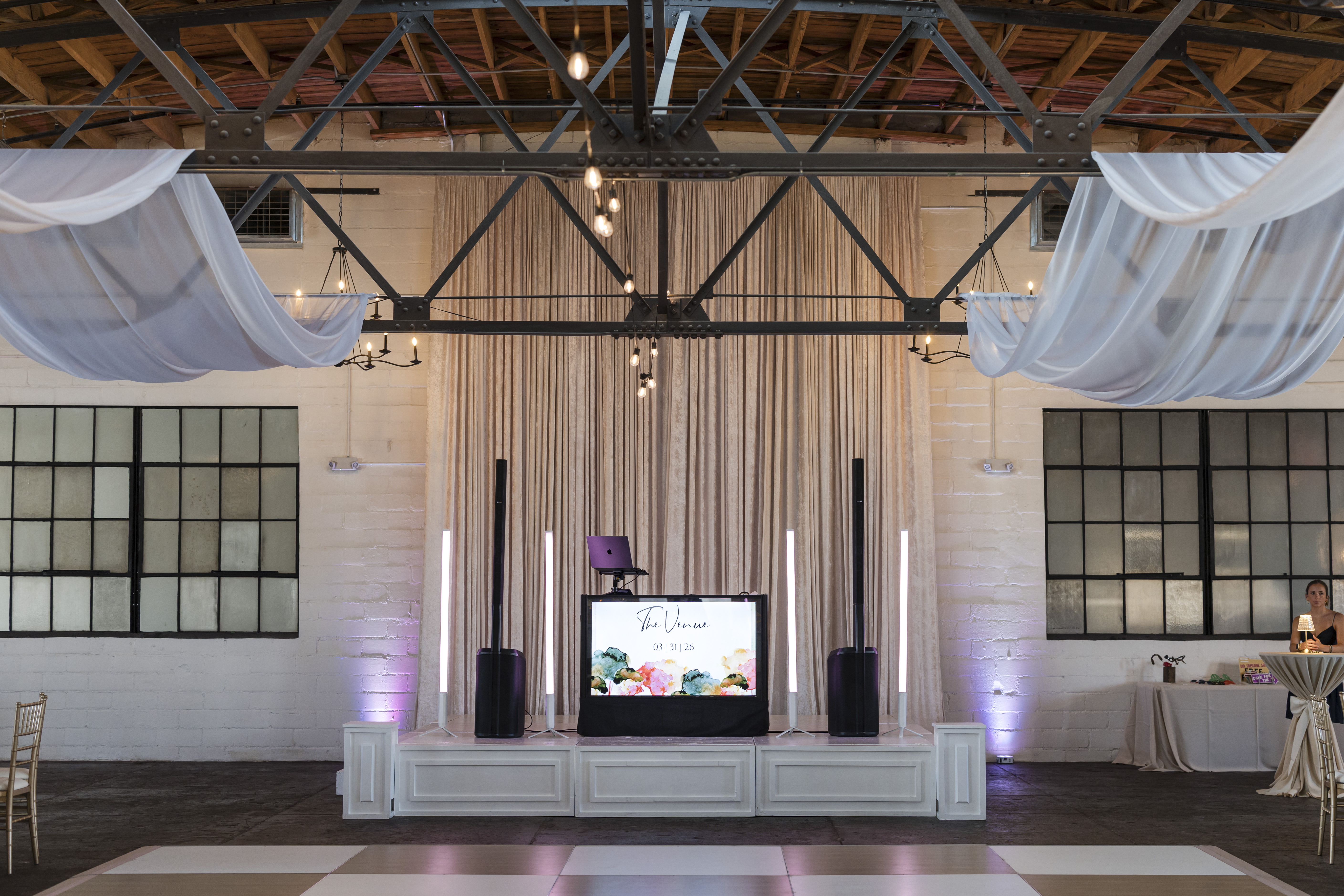 Footloose Entertainment DJ booth setup at The Venue Hastings with The Venue welcome screen, white booth facade, and industrial truss ceiling