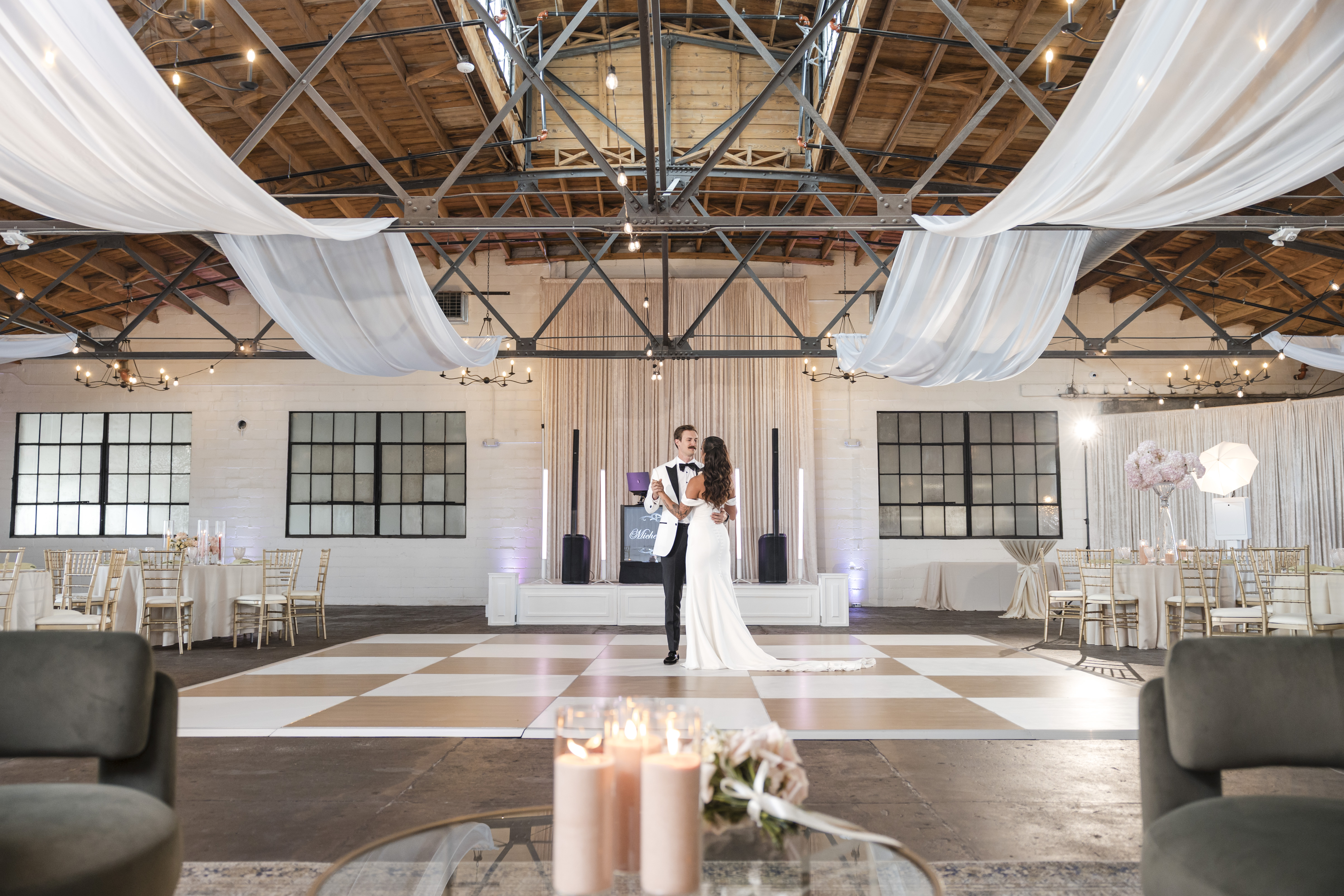 Couple sharing first dance in the Great Room at The Venue Hastings with full reception setup, lounge seating, and DJ booth visible