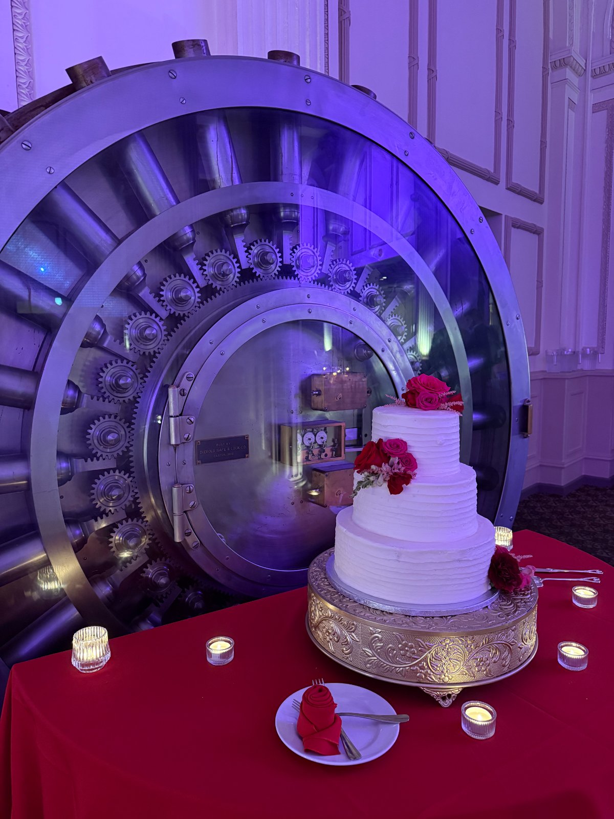 Wedding cake in front of the original bank vault with purple uplighting at Treasury on the Plaza St Augustine FL — Footloose Entertainment