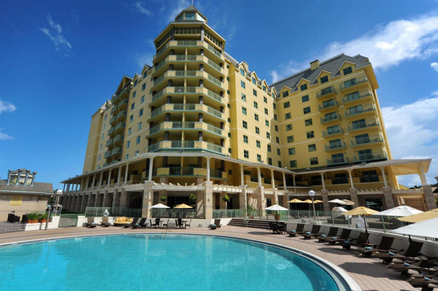 World Golf Village Renaissance St. Augustine Resort exterior, large yellow resort tower with balconies, outdoor pool with lounge chairs and umbrellas in the foreground